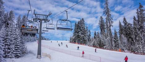 A ski lift with skiers and a snowy landscape with trees.