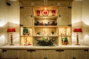 Un mueble de madera con estantes que contienen frascos de vidrio, una guirnalda decorativa y pequeñas figuritas.