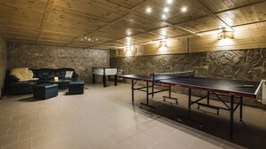 Een kamer met een tafeltennistafel, een bank en een stenen muur.
