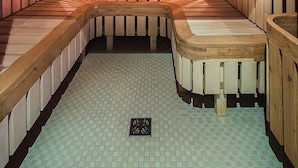 Een houten sauna met banken en een betegelde vloer.