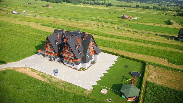 Een groot, meerlaags huis met een ruime oprit en een verzorgd gazon.