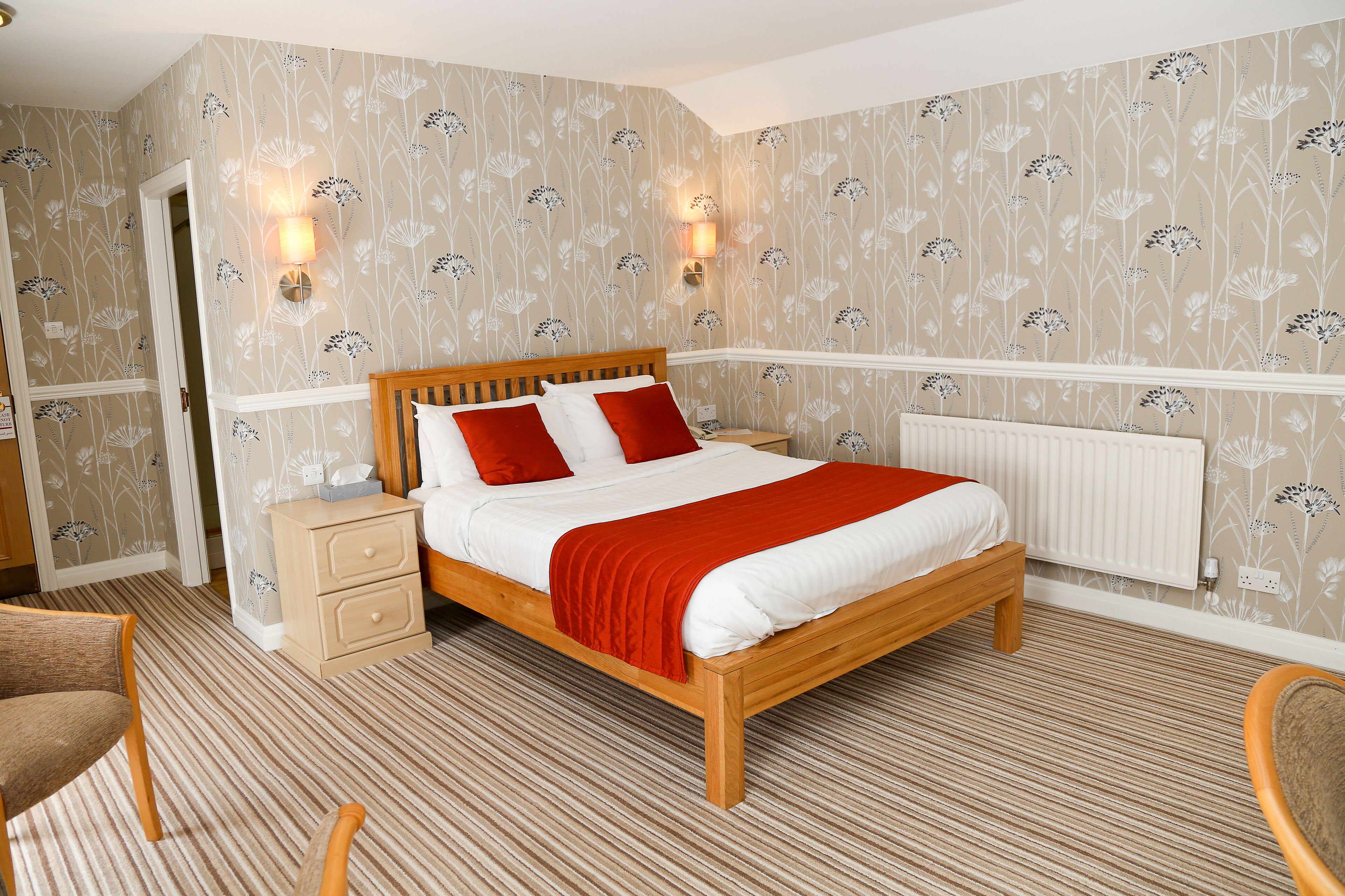 Un dormitorio ordenado con una cama de madera, dos mesitas de noche y un radiador.