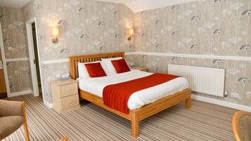 Un dormitorio ordenado con una cama de madera, dos mesitas de noche y un radiador.