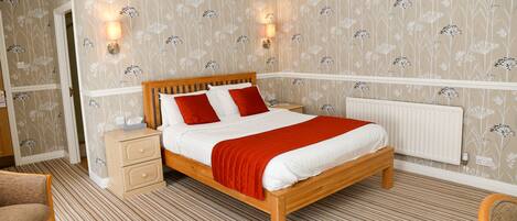 Un dormitorio ordenado con una cama de madera, dos mesitas de noche y un radiador.