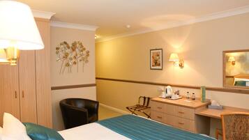 A hotel room with a bed, a desk, a chair, a wardrobe, and wall-mounted lamps.