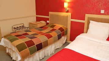 A hotel room with a bed, a bedside table, a lamp, and a wall with floral wallpaper.