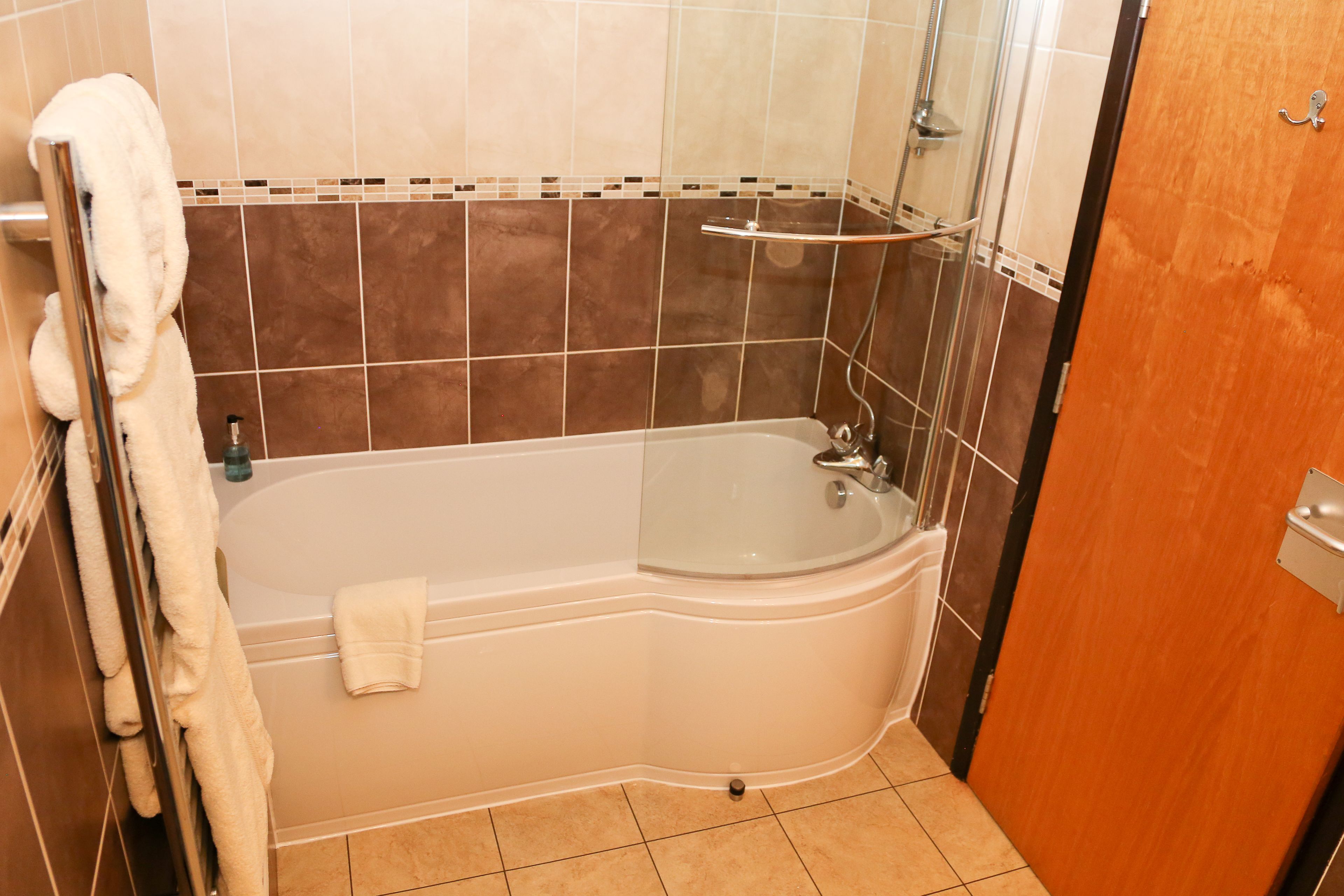 A bathroom with a bathtub, a shower, and a towel rack.
