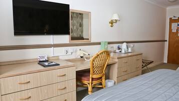 Ein Hotelzimmer mit Bett, Schreibtisch mit Stuhl, Fernseher, Spiegel, Lampe und einem Schild mit Rauchverbot.
