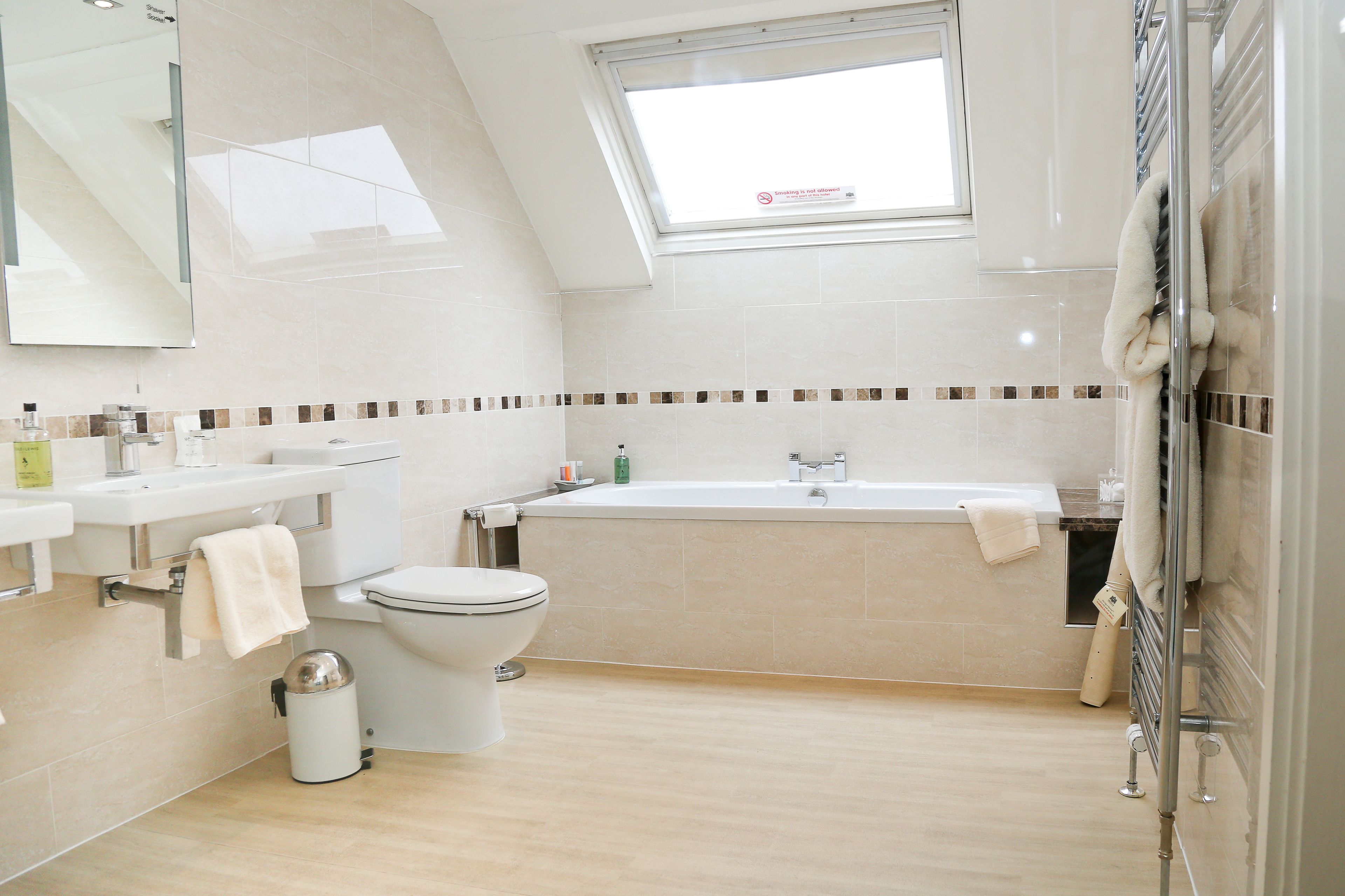Un baño moderno con tragaluz, bañera, inodoro y lavamanos.