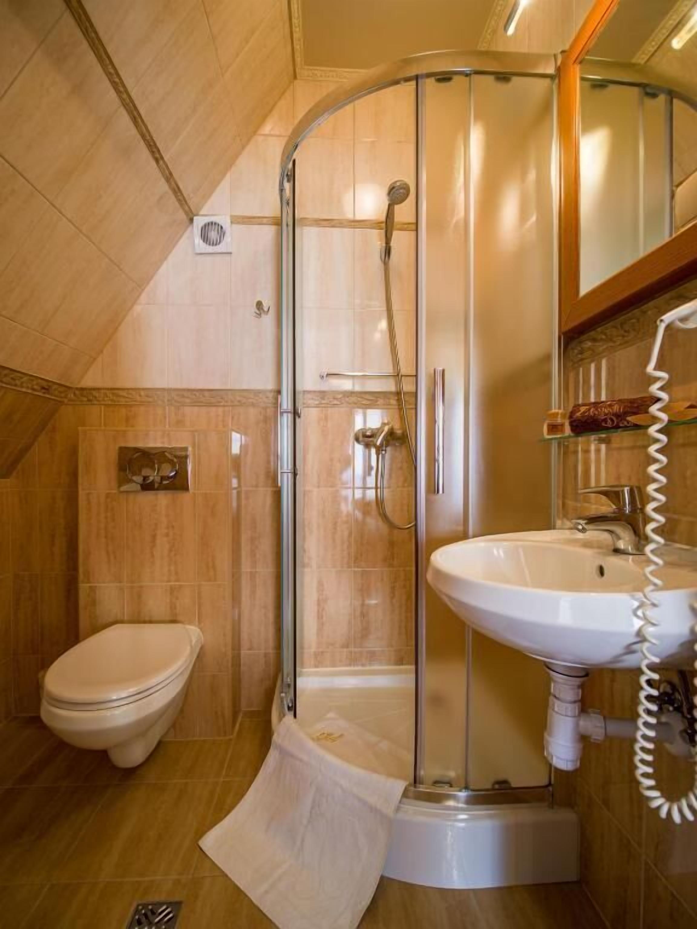 A bathroom with a glass-enclosed shower, a toilet, and a sink.
