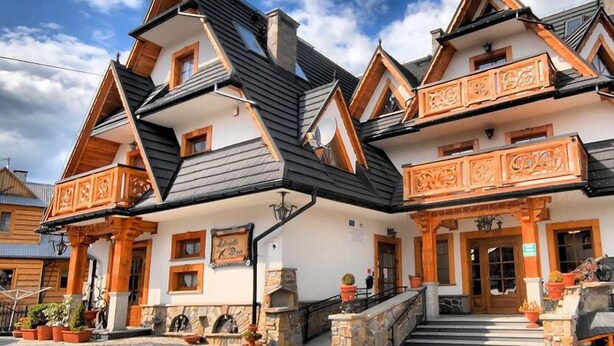Un hôtel de style chalet traditionnel, doté d’une façade symétrique, de toits à forte pente et de balcons en bois richement décorés.