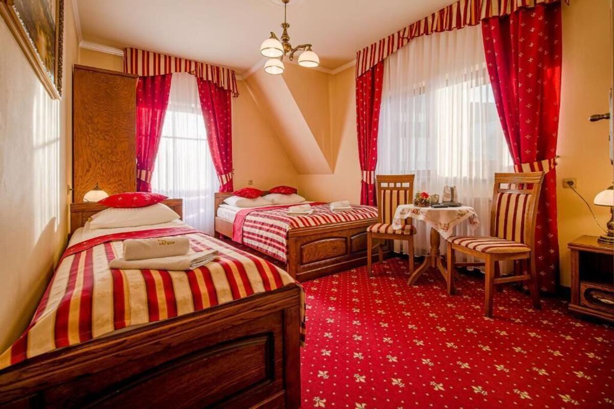 Une chambre d’hôtel avec deux lits simples, une petite table, une chaise et un bureau avec une lampe.