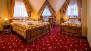 Une chambre d’hôtel avec deux lits en bois, une moquette rouge, des rideaux et une petite table.