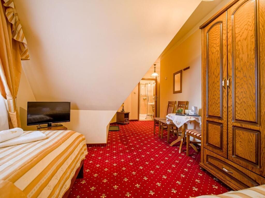 Ein Hotelzimmer mit einem Bett, einem Fernseher, einem Esstisch mit Stühlen und einem Kleiderschrank.