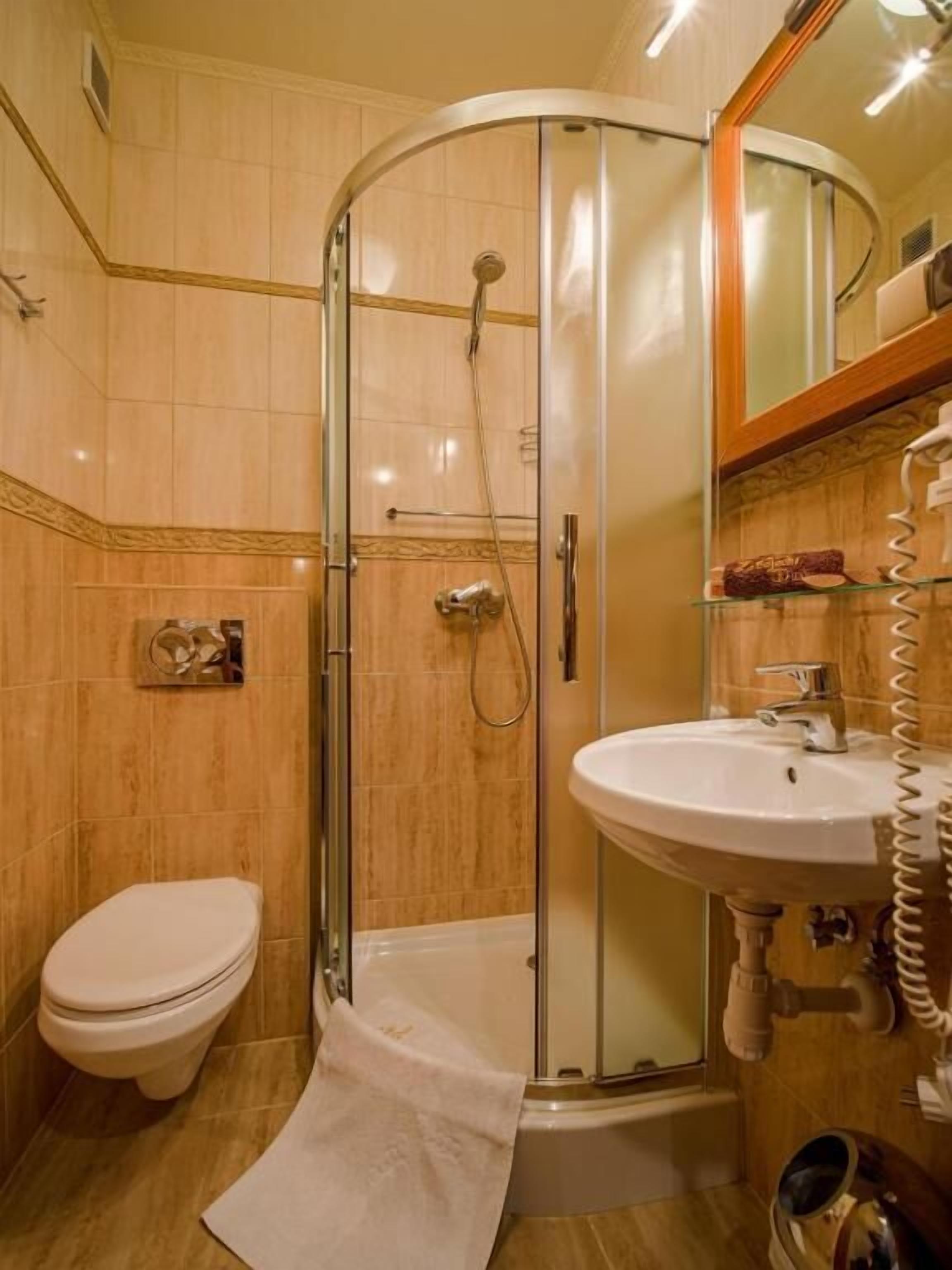 A modern bathroom with a glass-enclosed shower, a white toilet, and a sink with a mirror above it.