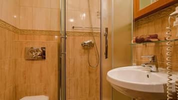 A modern bathroom with a glass-enclosed shower, a white toilet, and a sink with a mirror above it.