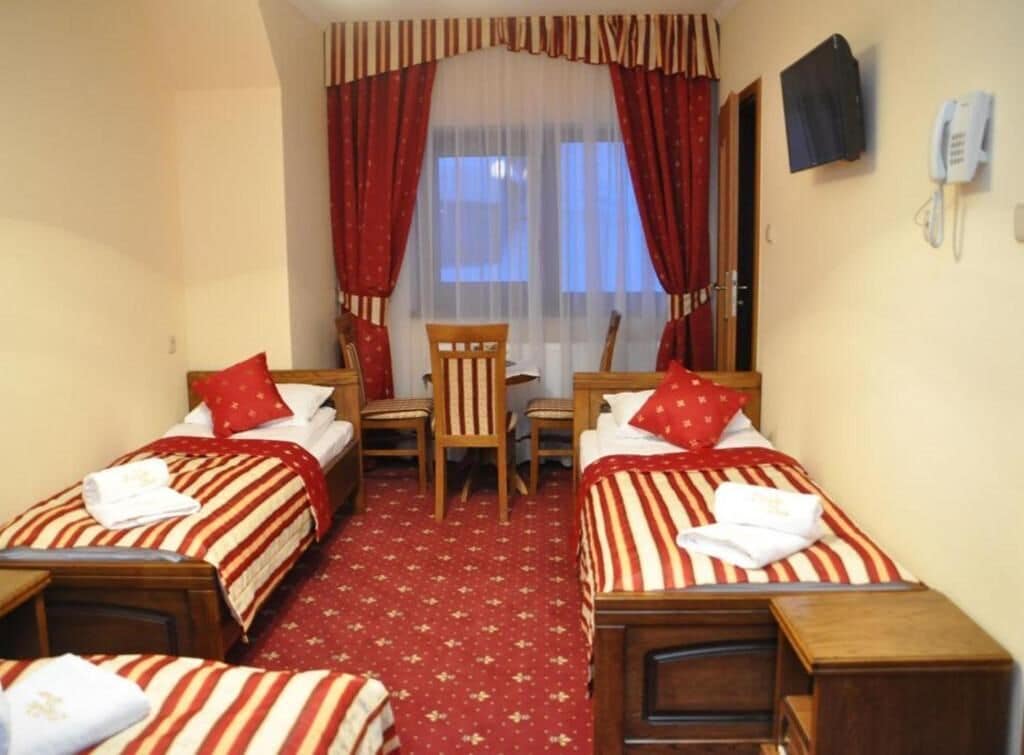 Habitación de hotel con dos camas individuales, un escritorio, una silla y un teléfono en la pared.