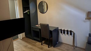 Un espace de salle à manger moderne avec une table et des chaises, un grand miroir rond au mur et un luminaire suspendu au plafond.
