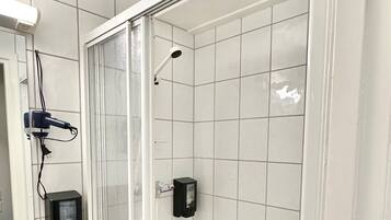 A bathroom with a glass-enclosed shower, a white sink, and a mirror.