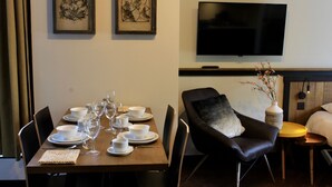 A dining area with a set table, chairs, and a flat-screen TV mounted on the wall.