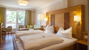 A hotel room with a large bed, two bedside tables, a desk, and a chair. - Gasthof Schorn (Groedig)