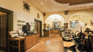 A kitchen with wooden cabinets, a coffee station, and a large island with a cutting board and a frying pan. - Gasthof Schorn (Groedig)