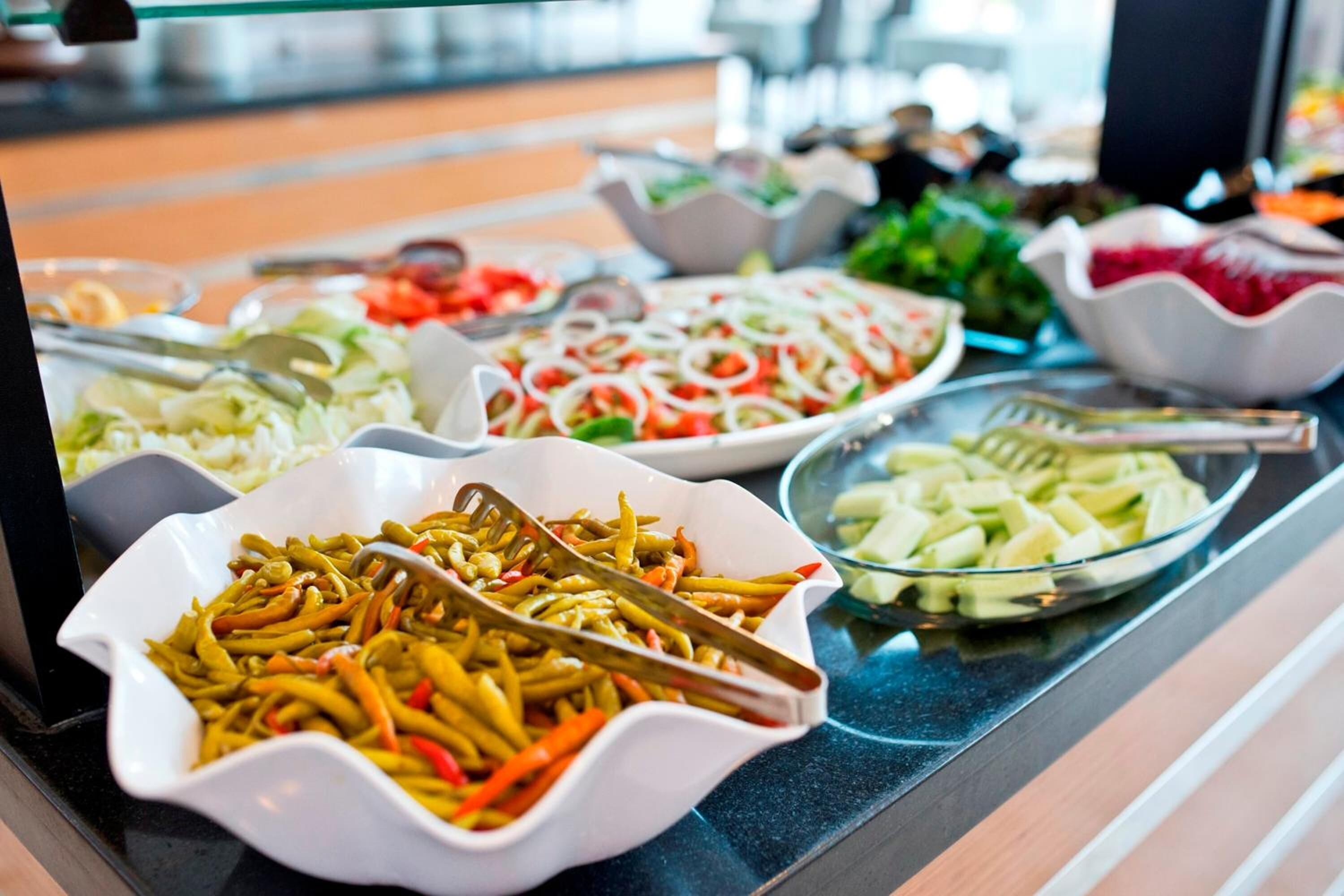 A buffet with various dishes including salads, pasta, and vegetables.
