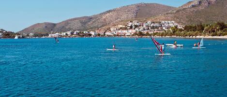 A coastal area with people windsurfing and sailing.