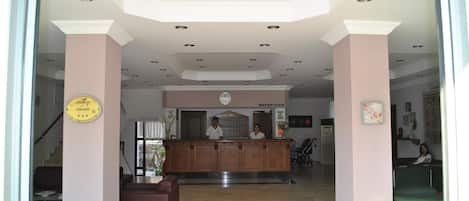 A hotel reception area with a reception desk, a clock, and a reception sign.