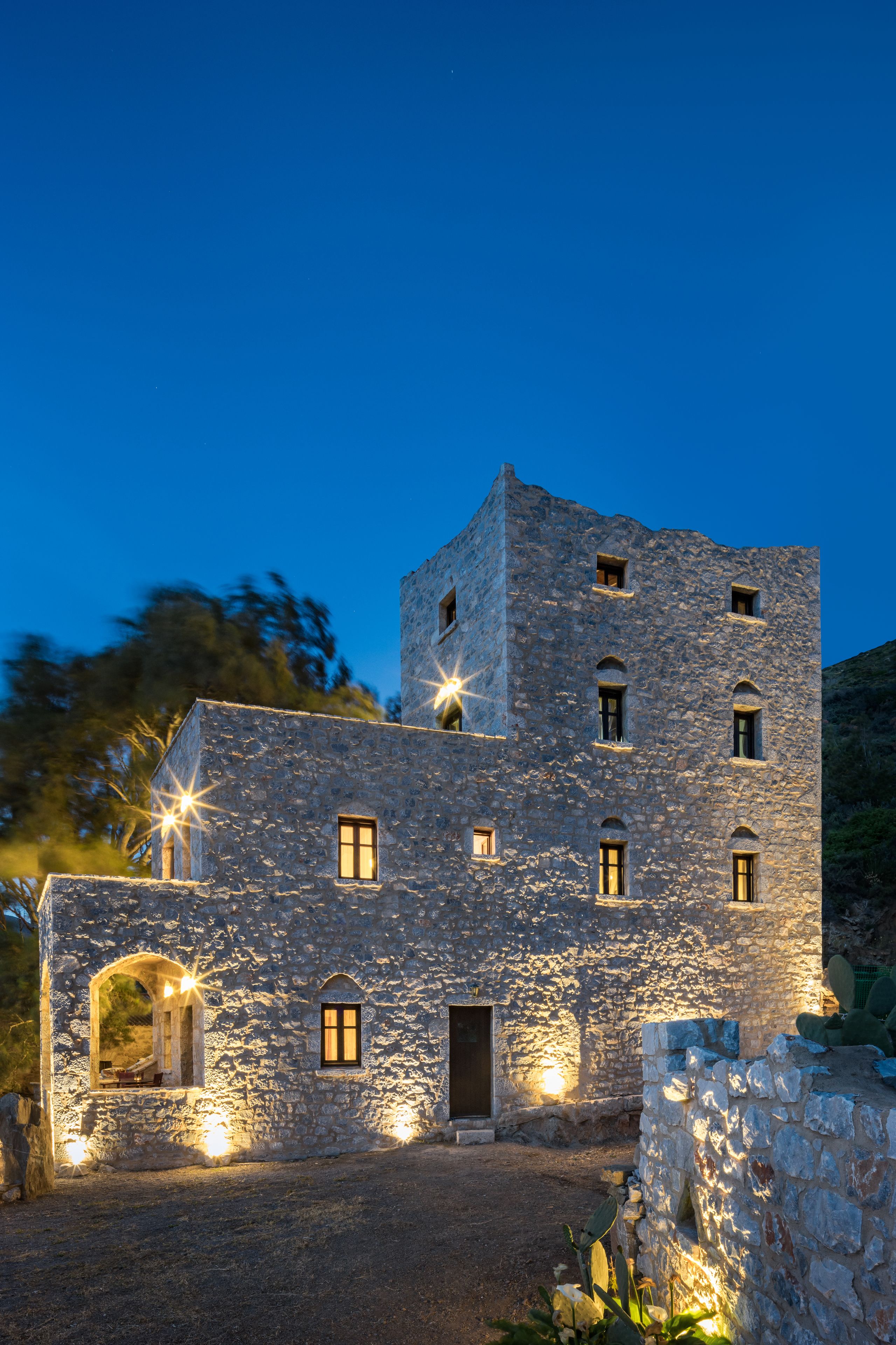 Un edificio de piedra con varias ventanas y una puerta, iluminado por luces exteriores.