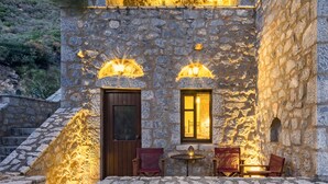 Un edificio de piedra con una escalera que conduce a un segundo piso, una puerta de madera y una pequeña mesa con sillas afuera.