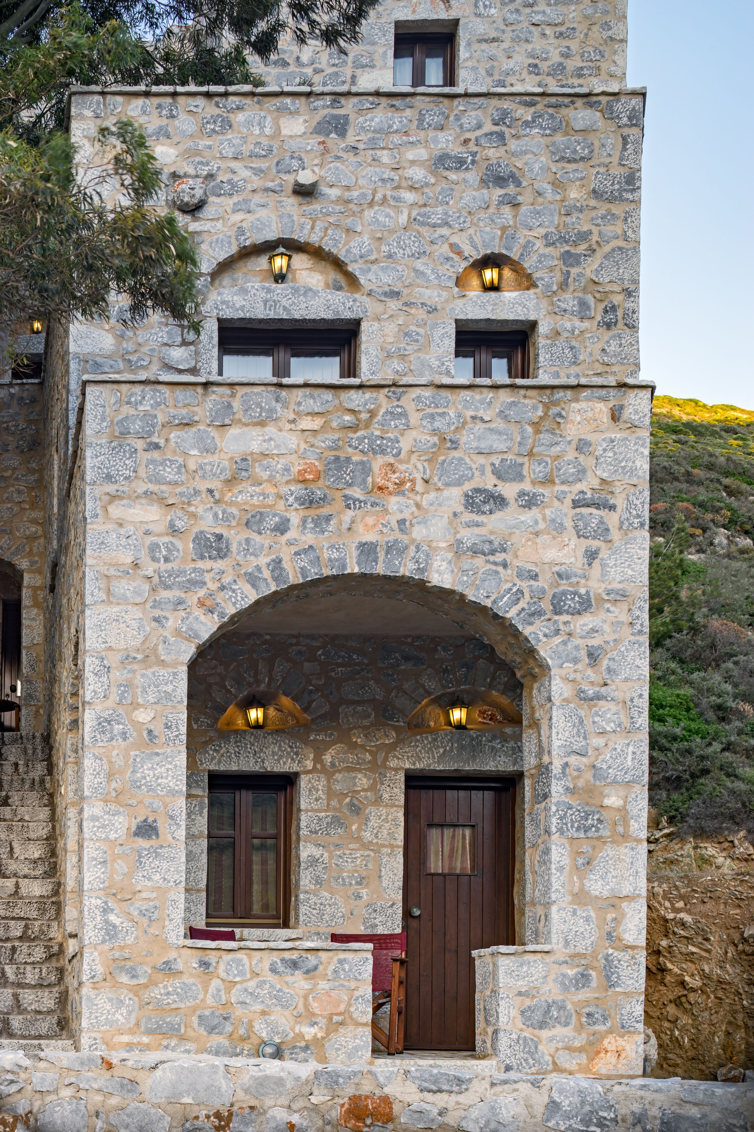 A stone building with two arched doorways and windows, each with a light fixture above.