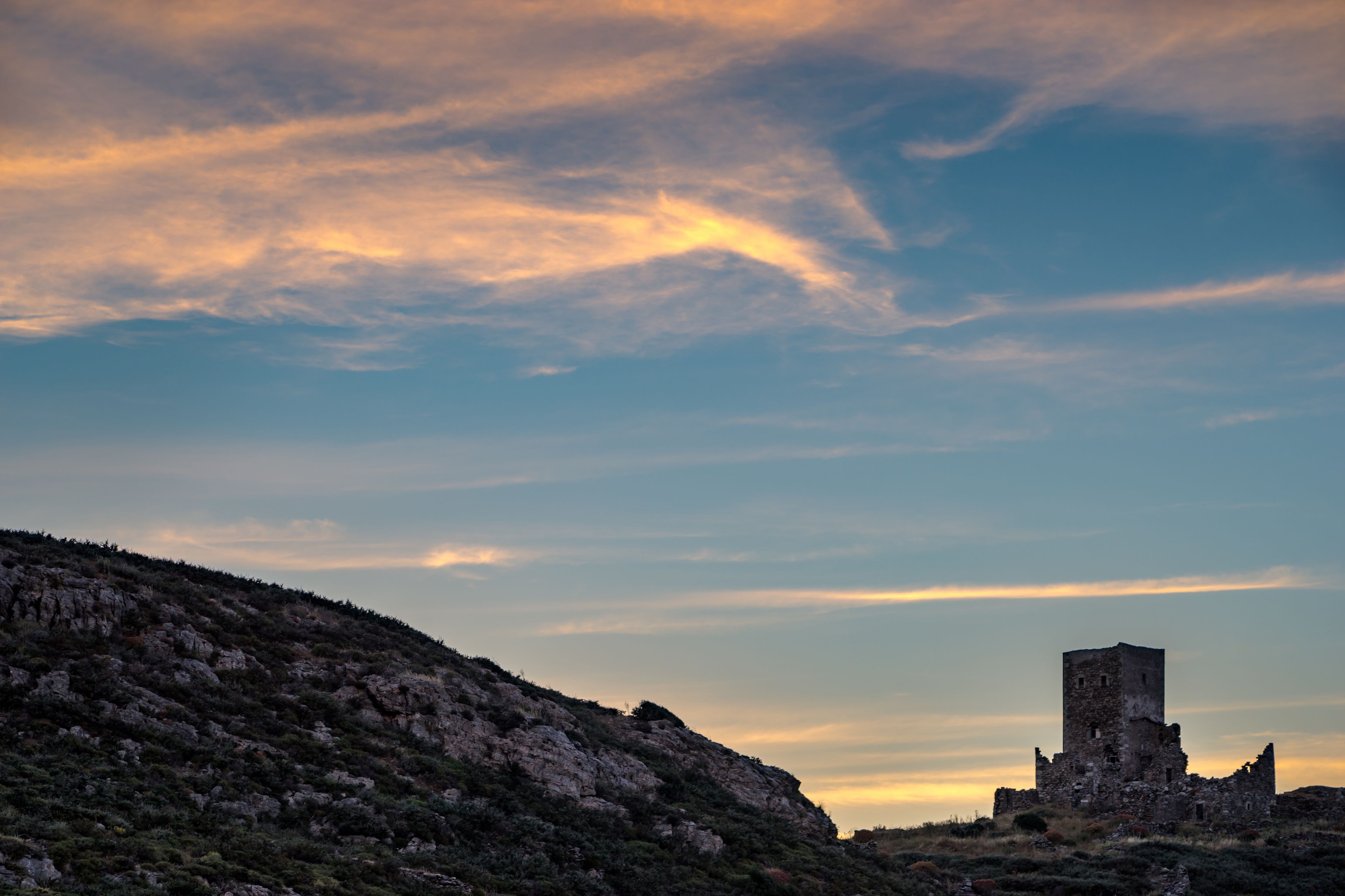 Una estructura de piedra histórica en una colina, con cielo despejado.