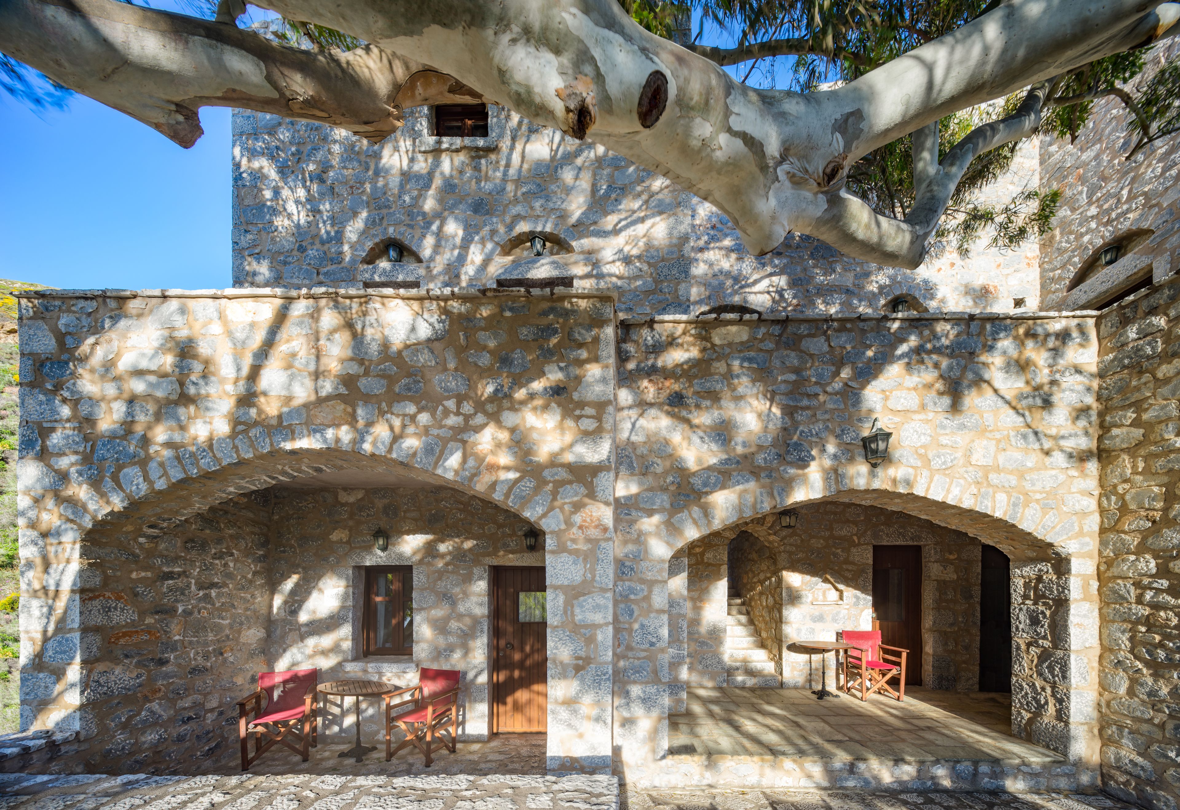 Un edificio de piedra con puertas arqueadas y una mesa con sillas en el patio.