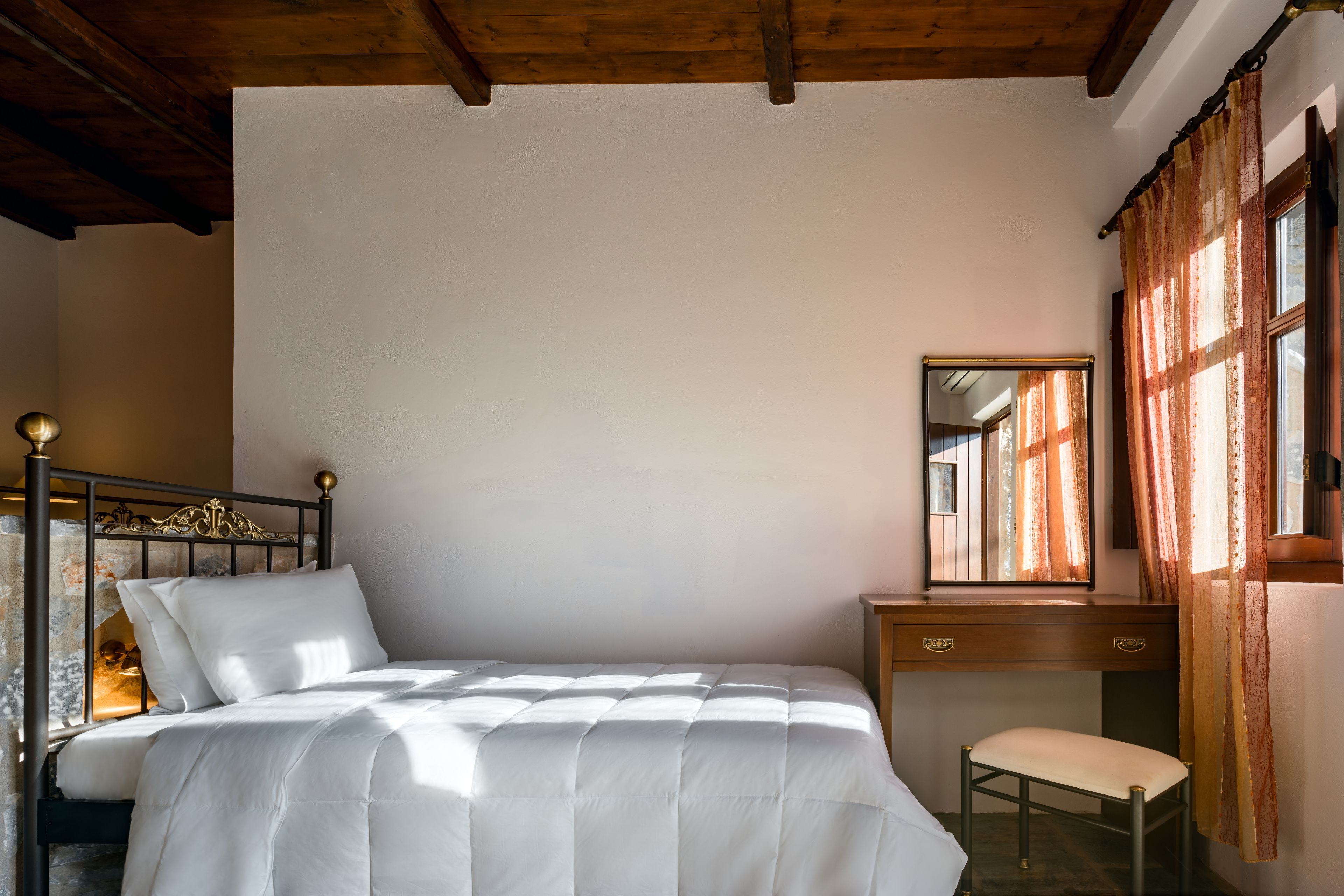 Una camera da letto con un letto, una scrivania in legno, una sedia e uno specchio.