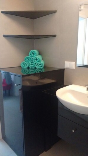 Un bagno con un armadietto nero, un lavandino bianco e uno specchio sopra.