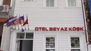 A white building with a sign reading "OTEL BEYAZ KOSK" and multiple flags. - Beyaz Kosk Hotel (Istanbul)