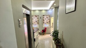 A hallway with a ceiling sign indicating an exit, a reception desk, a red chair, and potted plants. - Beyaz Kosk Hotel (Istanbul)