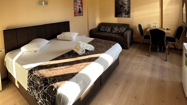 A hotel room with a large bed, a sofa, a small table with chairs, and a painting on the wall. - Beyaz Kosk Hotel (Istanbul)