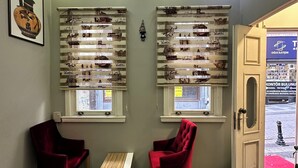 A room with two red chairs, a small wooden table, and shelves with decorative items. - Beyaz Kosk Hotel (Istanbul)