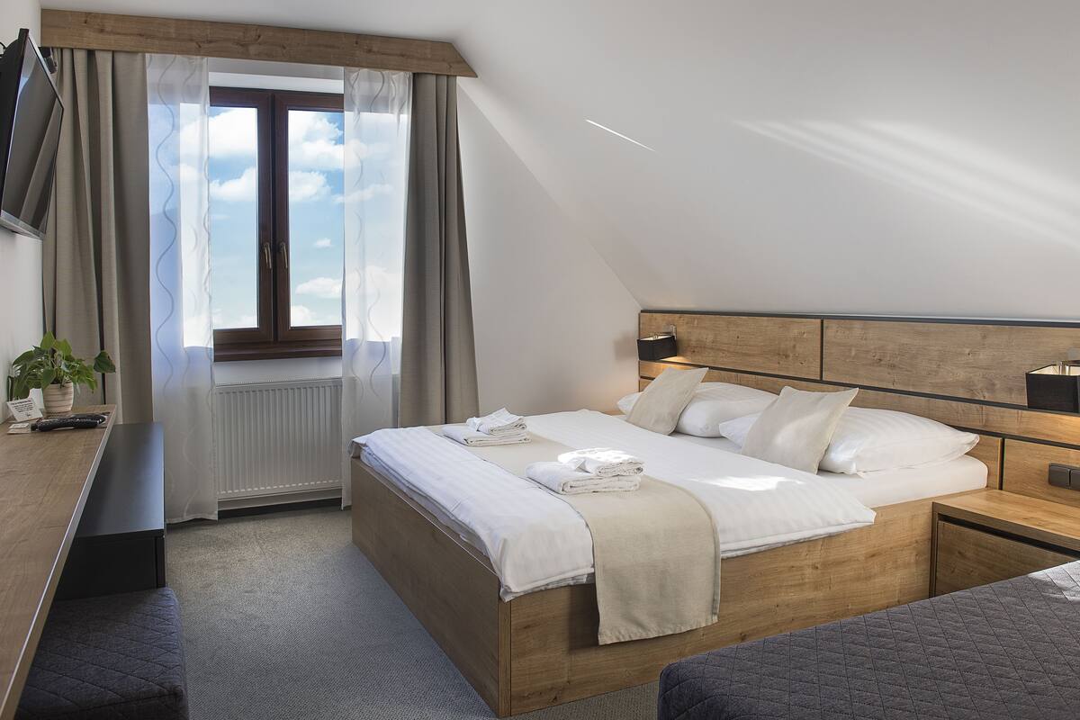 Ein modernes Schlafzimmer mit einem hölzernen Bett, einem Nachttisch, einem Schreibtisch und einem Fenster mit Vorhängen.