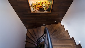 Una escalera de madera con barandilla moderna y un cuadro de girasoles en la pared superior.