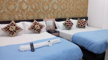 A hotel room with two beds, each with a different colored bedspread, a nightstand with a phone and charger, and decorative pillows.