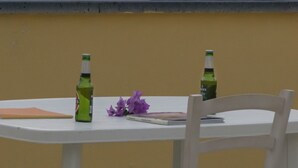 A table with two bottles and a notebook, overlooking a sunset over the sea. - Argentiera Inn (Sassari)