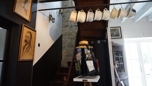 Un escalier orné d’un porte-ustensiles suspendu, de portraits encadrés, ainsi que d’une collection de livres et d’un chapeau.