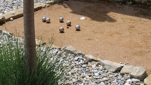 Un espace jardin aménagé avec un chemin de gravier, un poteau en bois et plusieurs objets sphériques.