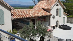 Une maison avec un toit en tuiles, un balcon et une vue sur la campagne.