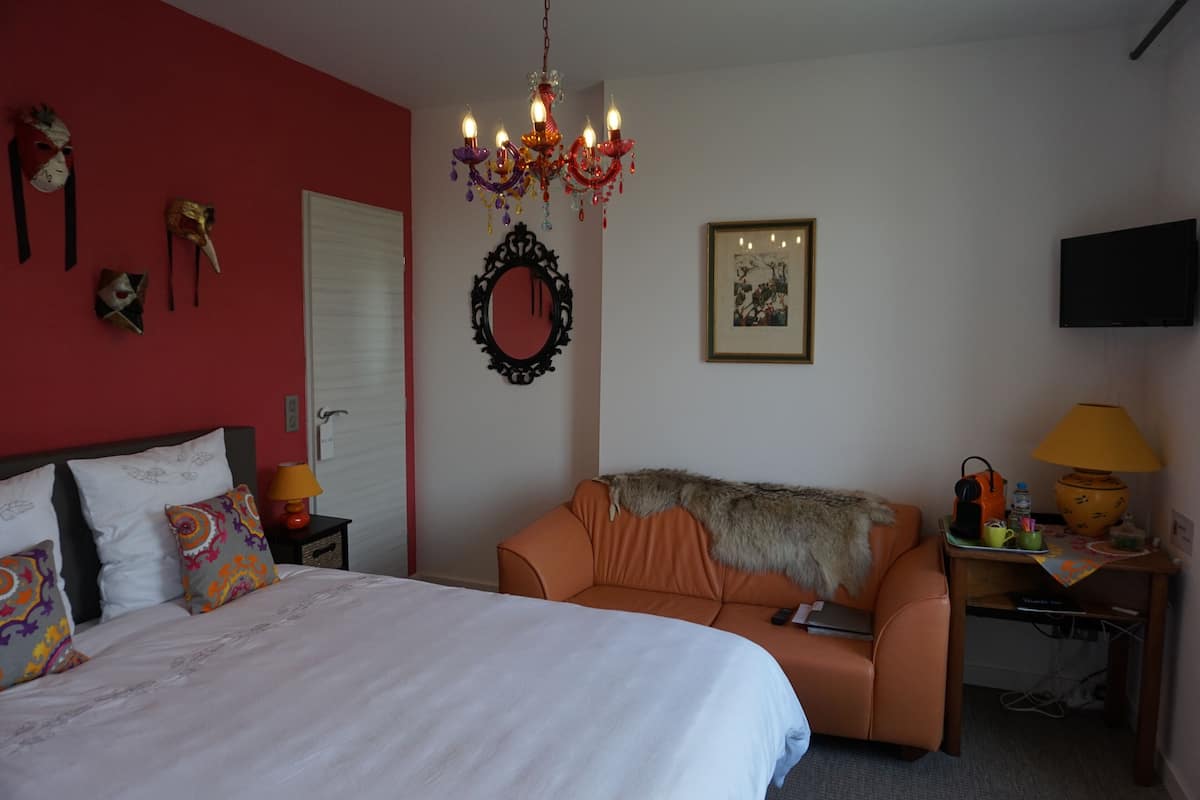 Een hotelkamer met een bed, een bank, een televisie, een lamp en een spiegel.
