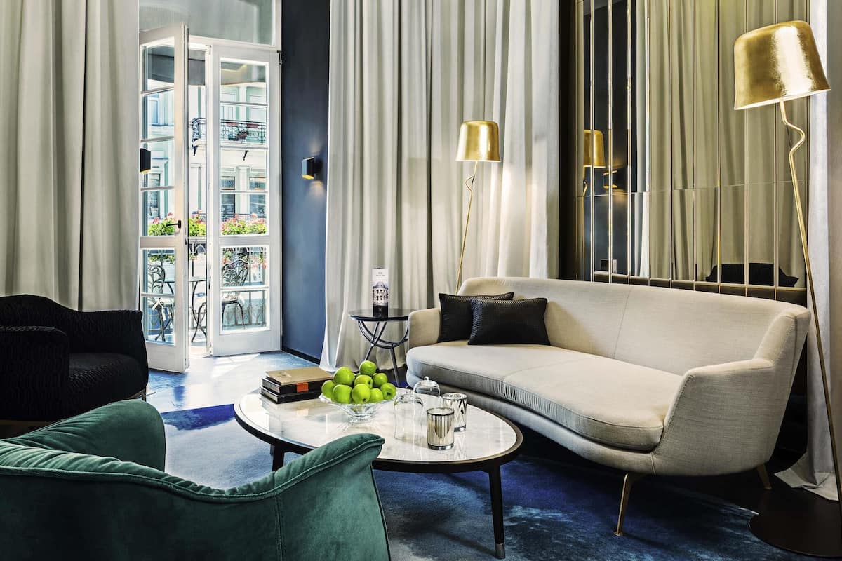 Una sala de estar moderna con sofá, sillón, mesa de centro y lámpara.