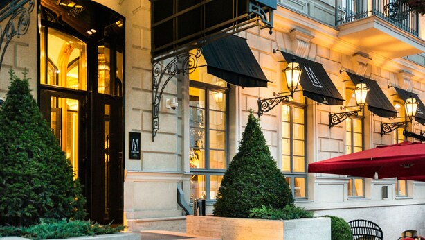 Exterior del Hotel de Paris con una entrada destacada, escalones que conducen a la puerta y un área de estar al aire libre.